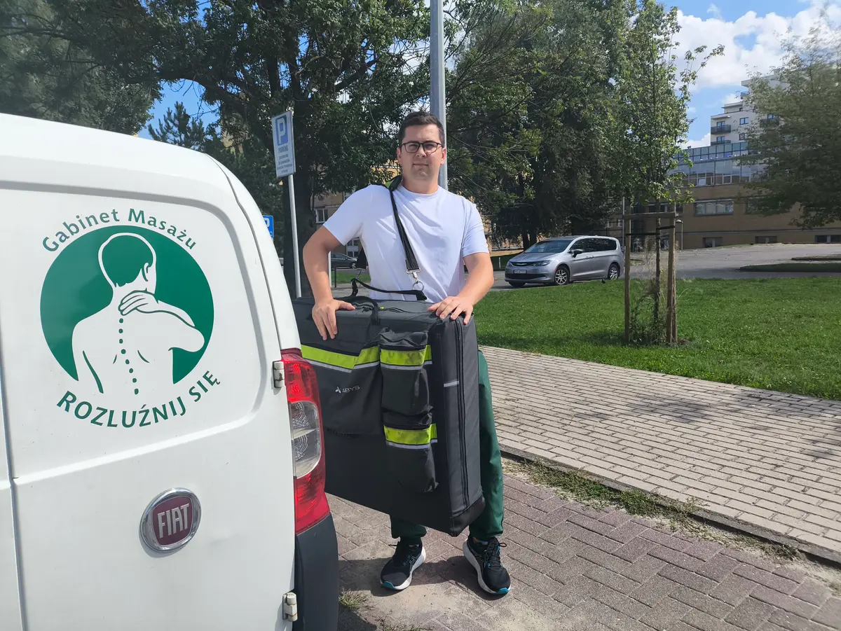 Masażysta wyjmuje z auta składany stół do masażu z dojazdem w Poznaniu